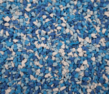 A close-up view of a textured surface covered in small blue, white, and light blue rubber granules mixed together.