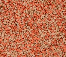 A close-up view of small, irregularly shaped granules in shades of orange and beige, resembling gravel or crushed stone, densely packed together.