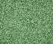 Close-up of small, irregular green rubber granules or chips, with a slightly rough texture, spread evenly across the entire image.