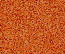 A close-up view of many small, irregular orange granules or pellets closely packed together, covering the entire image.