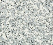 A close-up of a textured surface covered with small, irregularly shaped white and light gray rubber granules mixed together.