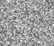 A close-up of a textured gray and white speckled surface, resembling small pebbles or granules tightly packed together, creating a rough, uneven pattern.